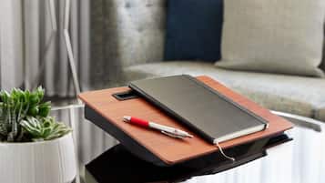 A wooden side table with a notebook, pen, and smartphone.
