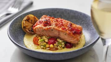 Un plato de salmón acompañado de maíz y tomates cherry.
