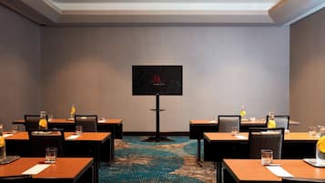 A conference room with a large screen, multiple tables, and chairs.