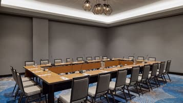 A conference room with a long table, chairs, and a ceiling light fixture.