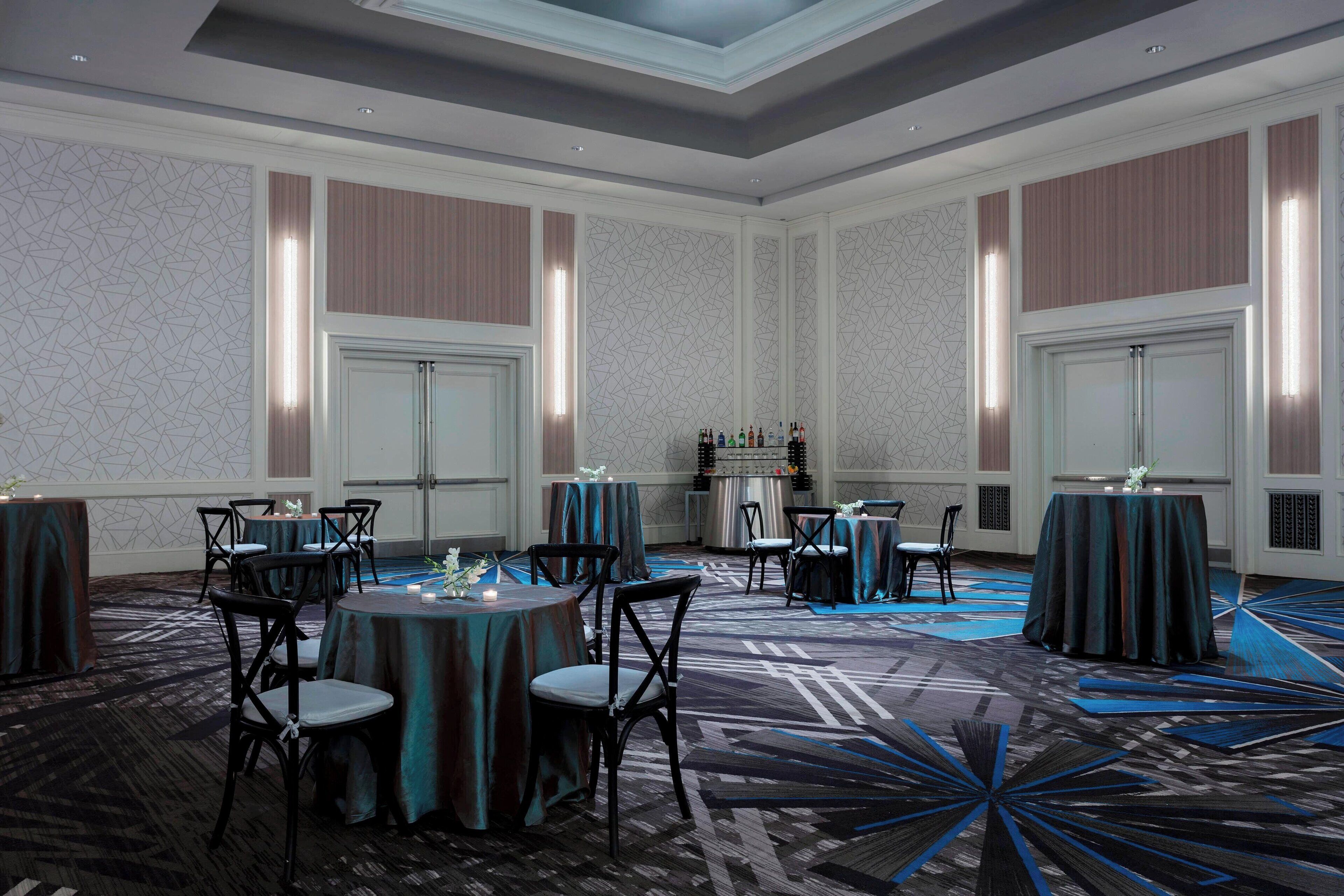 A spacious banquet hall with high ceilings, elegant chandeliers, and a patterned carpet.