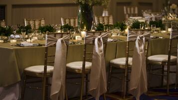 A banquet table set with chairs, candles, and floral centerpieces.