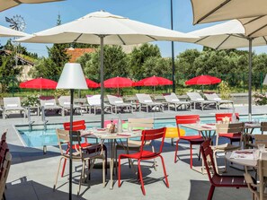 Relax by the pool surrounded by lounge chairs and umbrellas, with tables and chairs for dining or unwinding.