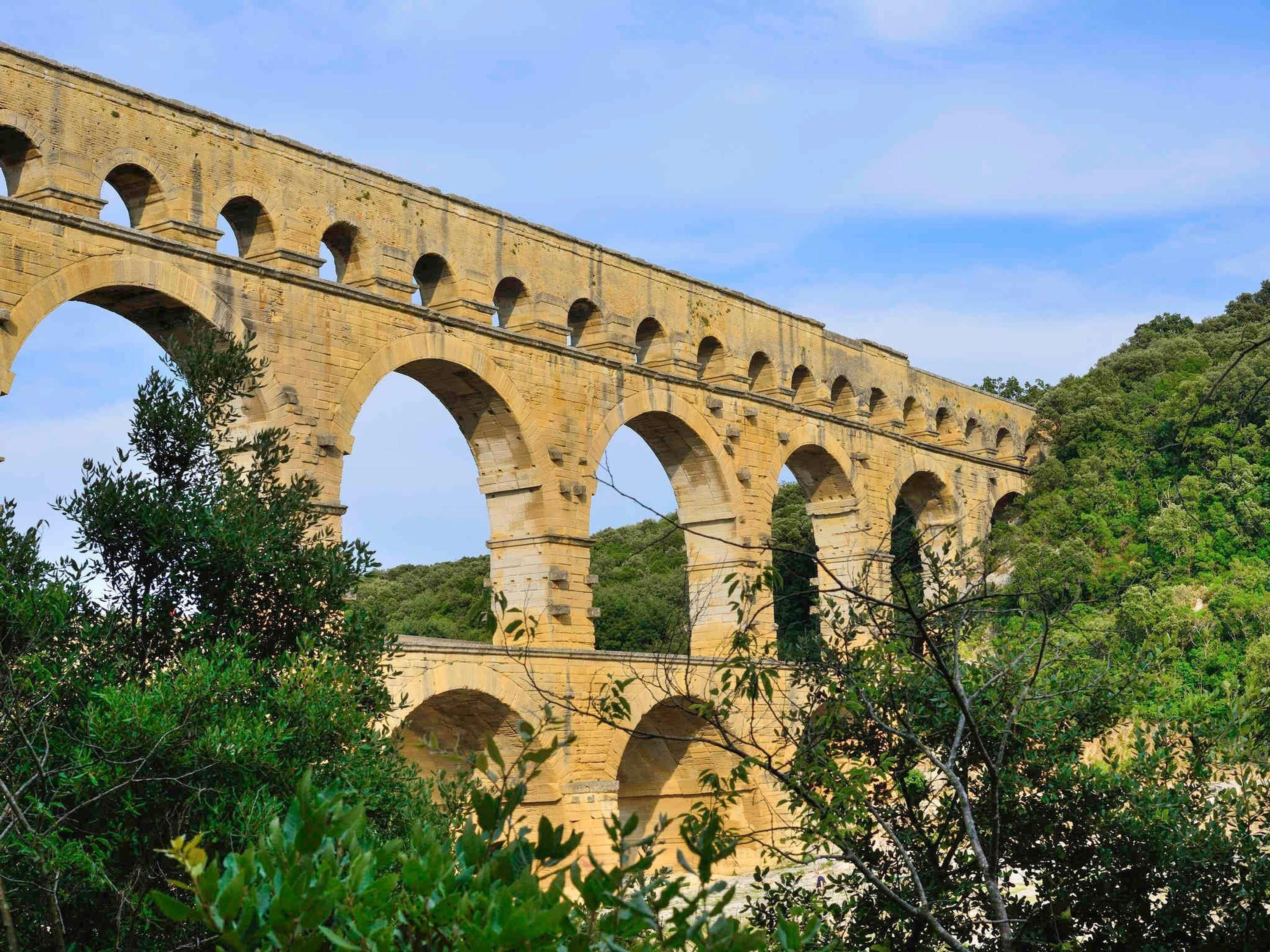 Un acquedotto in pietra con più archi, immerso nel verde.
