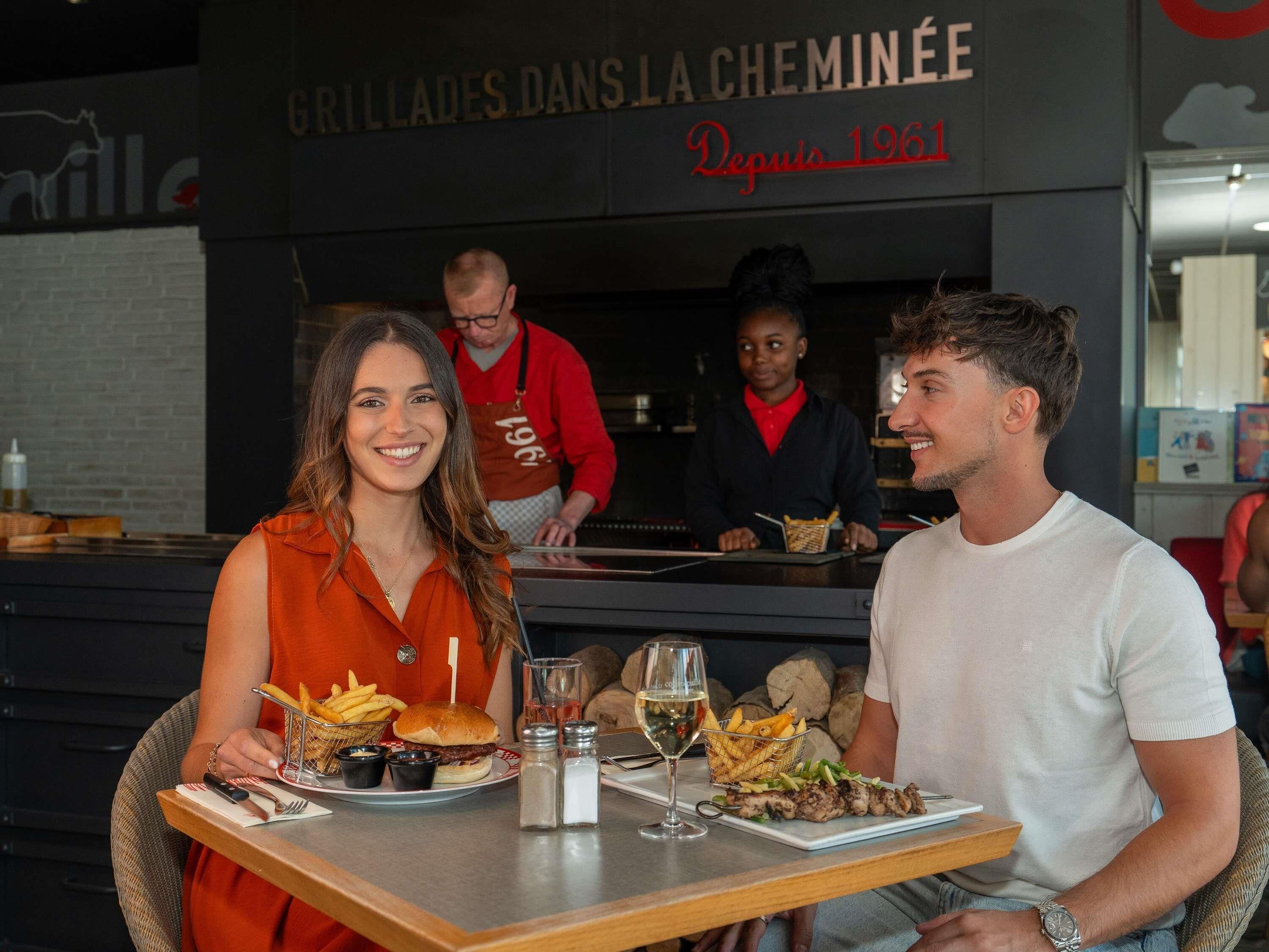 A restaurant with a sign reading 'GRILLADES DANS LA CHEMINÉE' and 'Depuis 1961'.