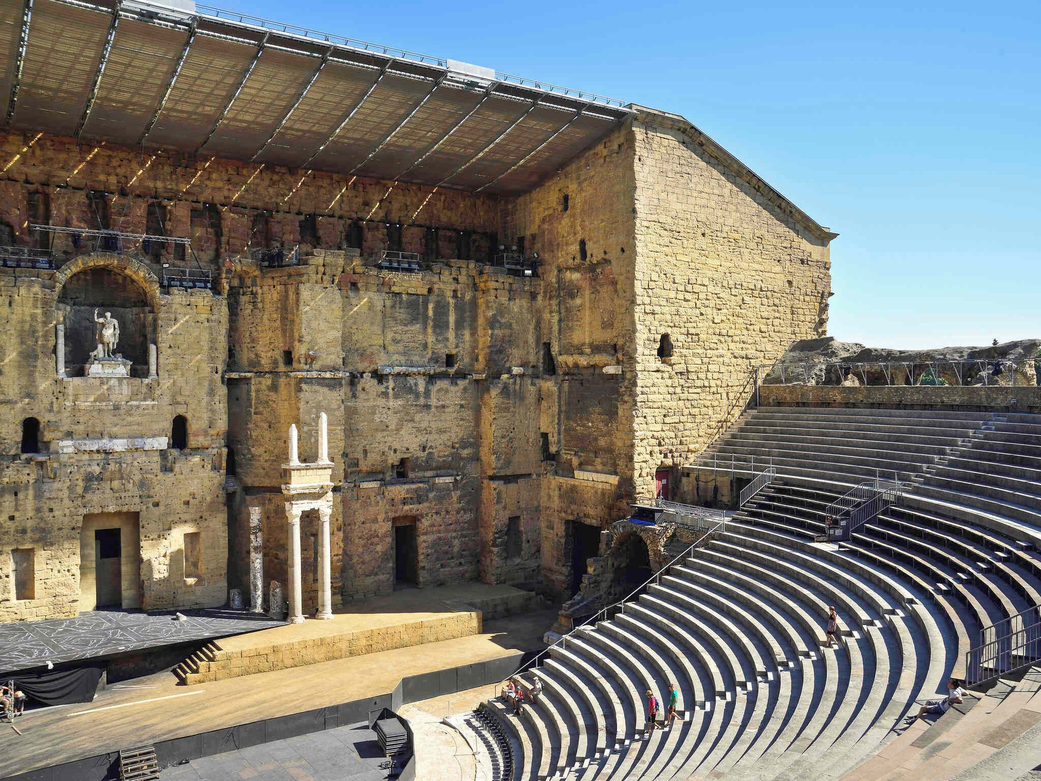 Un anfiteatro antiguo con asientos escalonados y fachada de piedra.