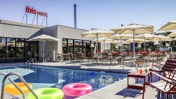 Una piscina al aire libre, sillones reclinables de piscina