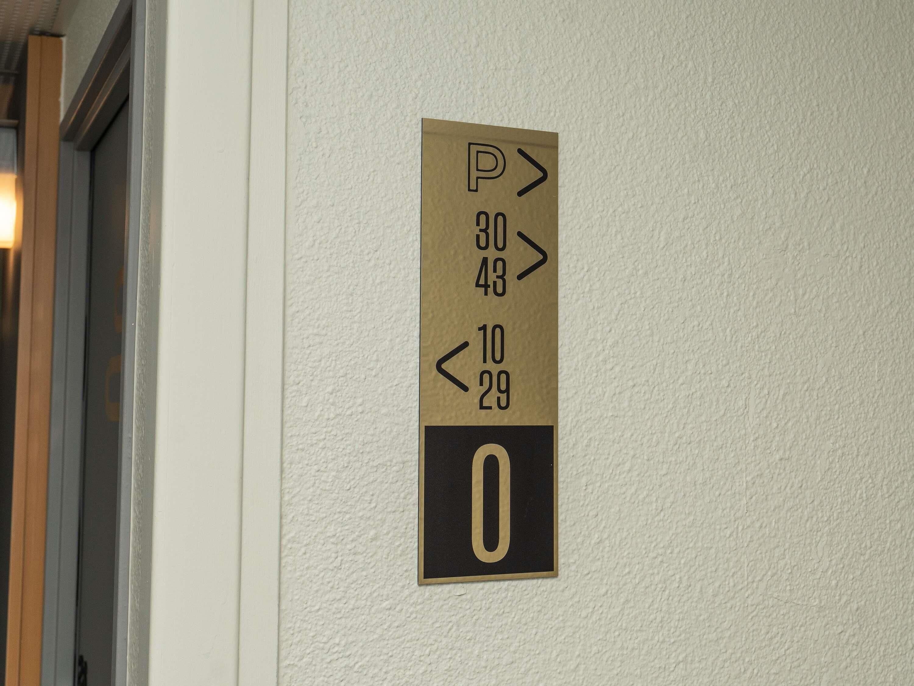 A wall-mounted parking sign with directional arrows and numbers indicating parking spaces.
