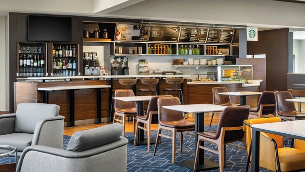 Un área de bar moderna con una variedad de botellas de licor, una estación de café y diferentes disposiciones de asientos.