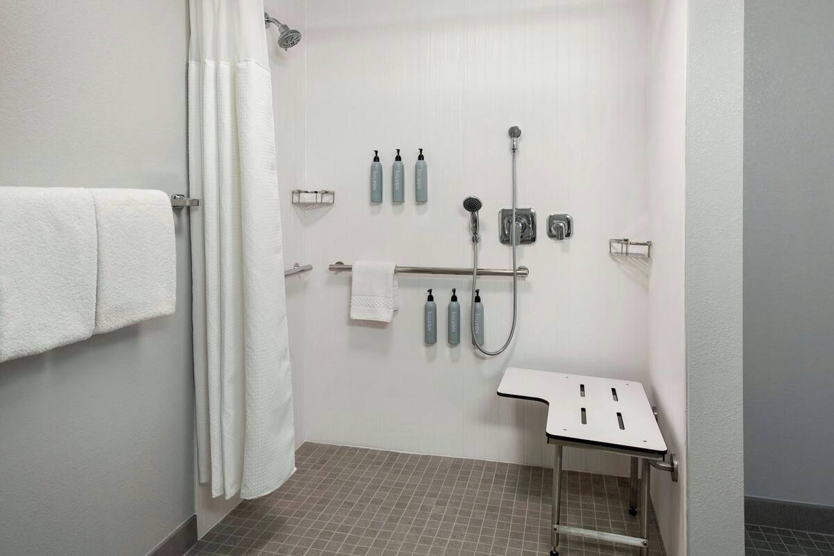 A bathroom with a shower, a towel rack, and a small table.