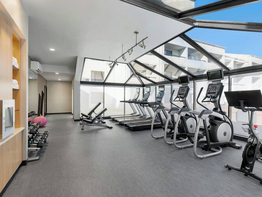 Un gimnasio con cintas de correr, elípticas y mancuernas.