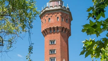 A historic brick tower with a turret, surrounded by traditional half-timbered buildings.