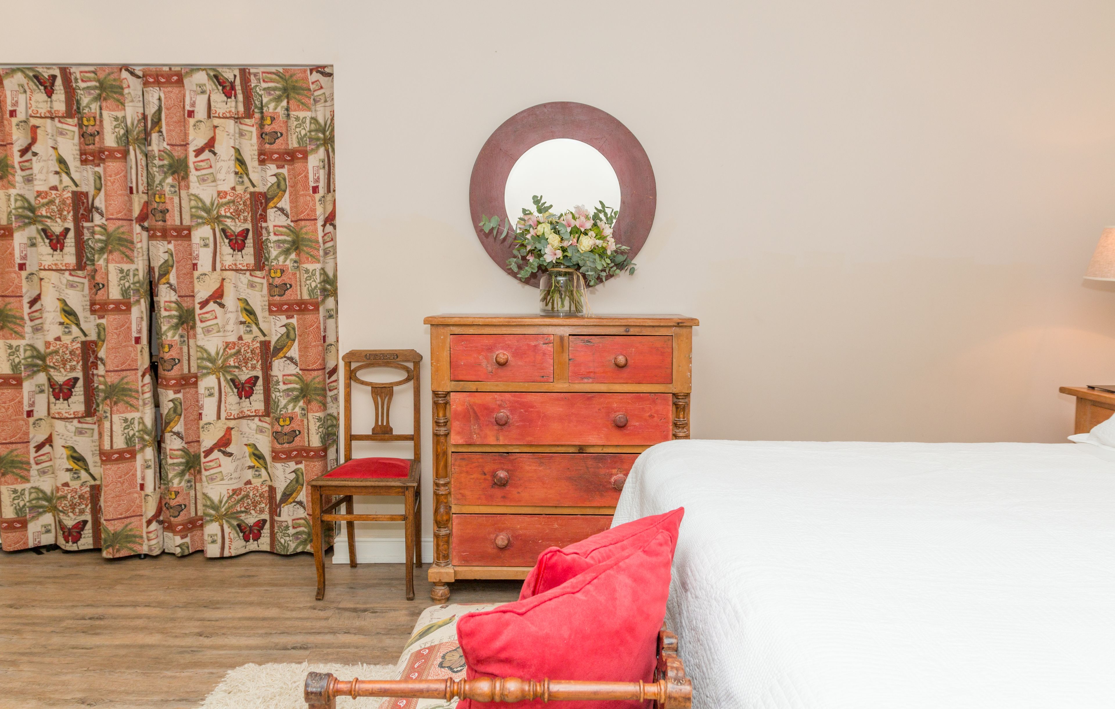 Un dormitorio con una cama, un aparador de madera, una silla y un espejo en la pared.