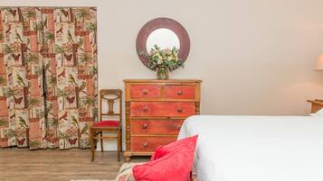 Un dormitorio con una cama, un aparador de madera, una silla y un espejo en la pared.