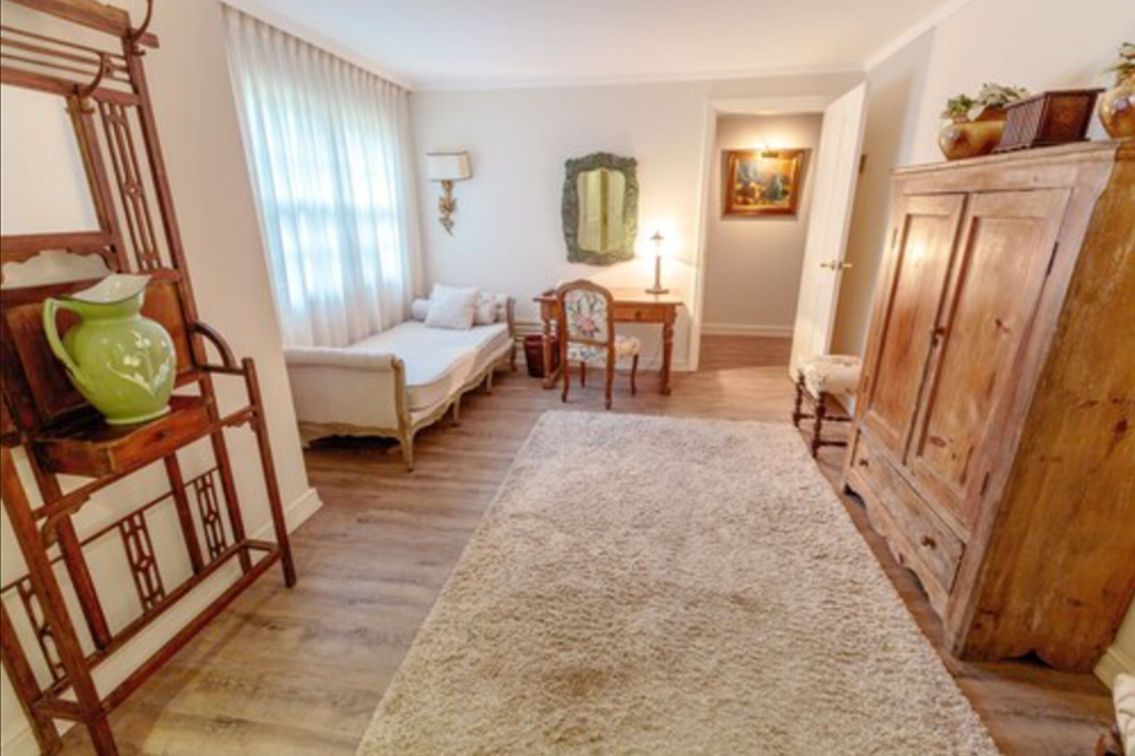 A cozy room with a bed, a desk, a chair, a cabinet, and a rug.