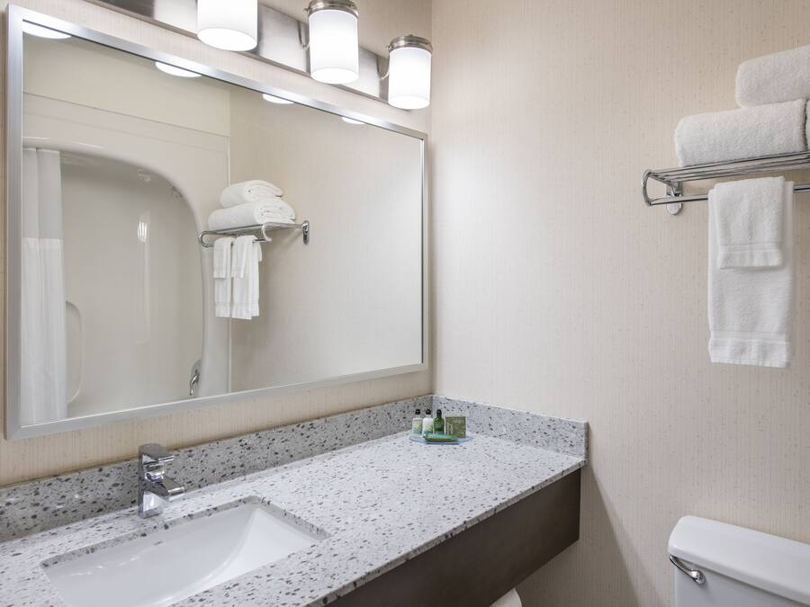 Un baño con un espejo grande, un lavabo y un perchero para toallas.