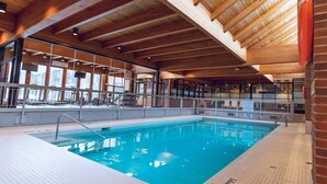 An indoor swimming pool with wooden beams and tiled flooring.