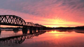 A steel bridge over a calm body of water at sunset.