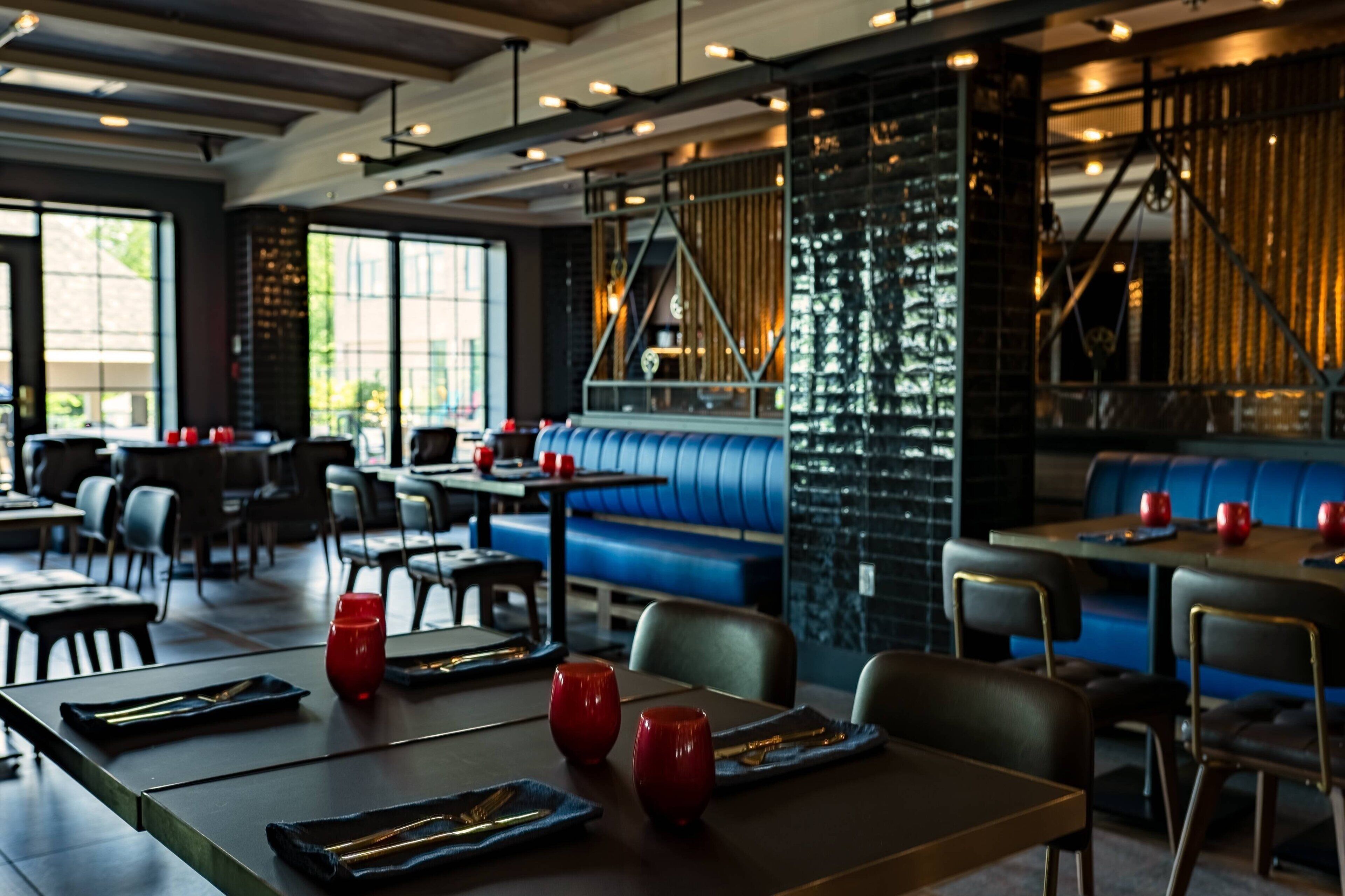 Interior de restaurante com mesas, cadeiras e área de assentos em azul.