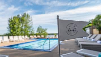 A flag with the logo and name of Drift Resort & Bar, a pool area with lounge chairs, and a clear sky.