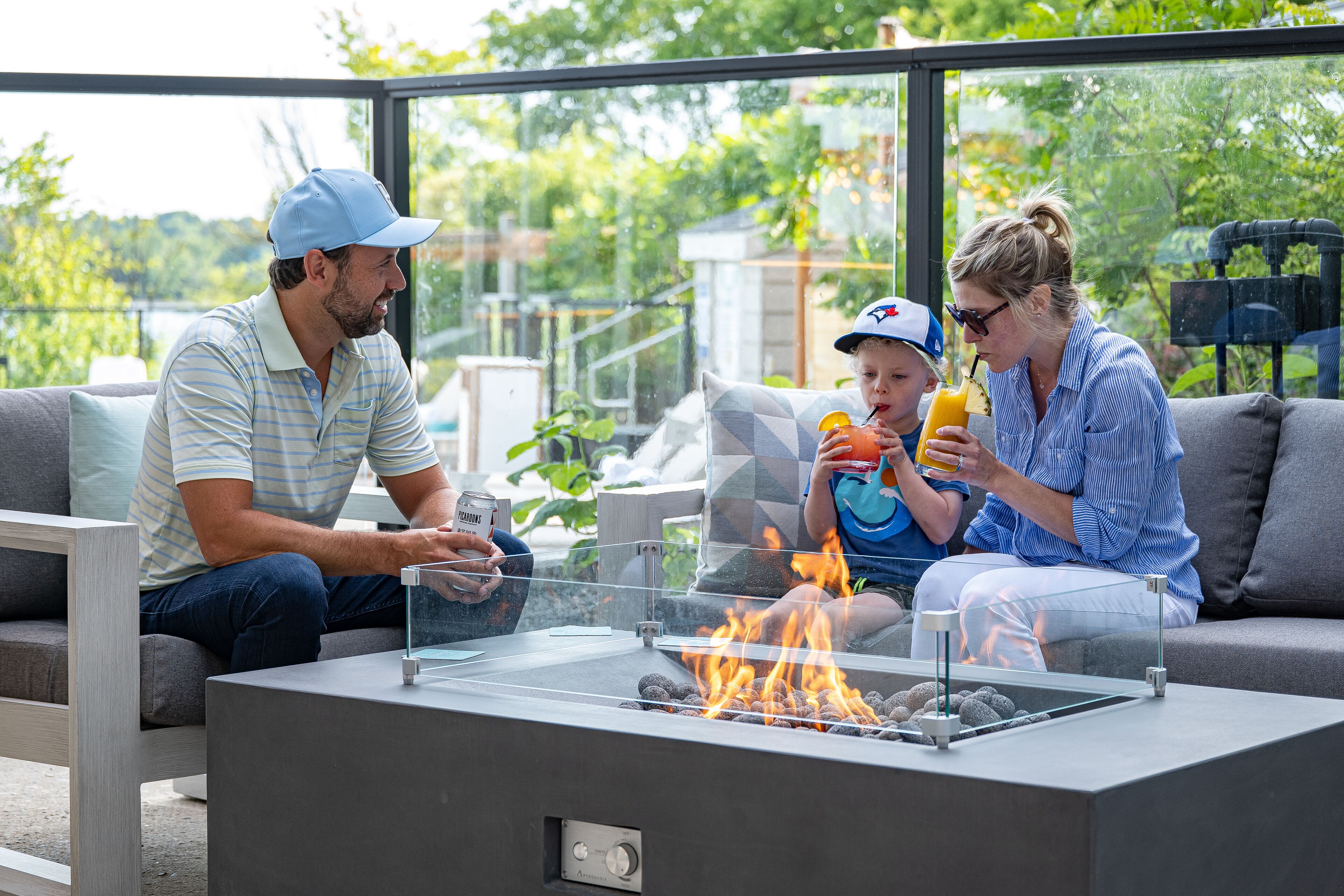 A modern outdoor seating area with a glass-top fire pit, comfortable seating, and a view of the outdoors.