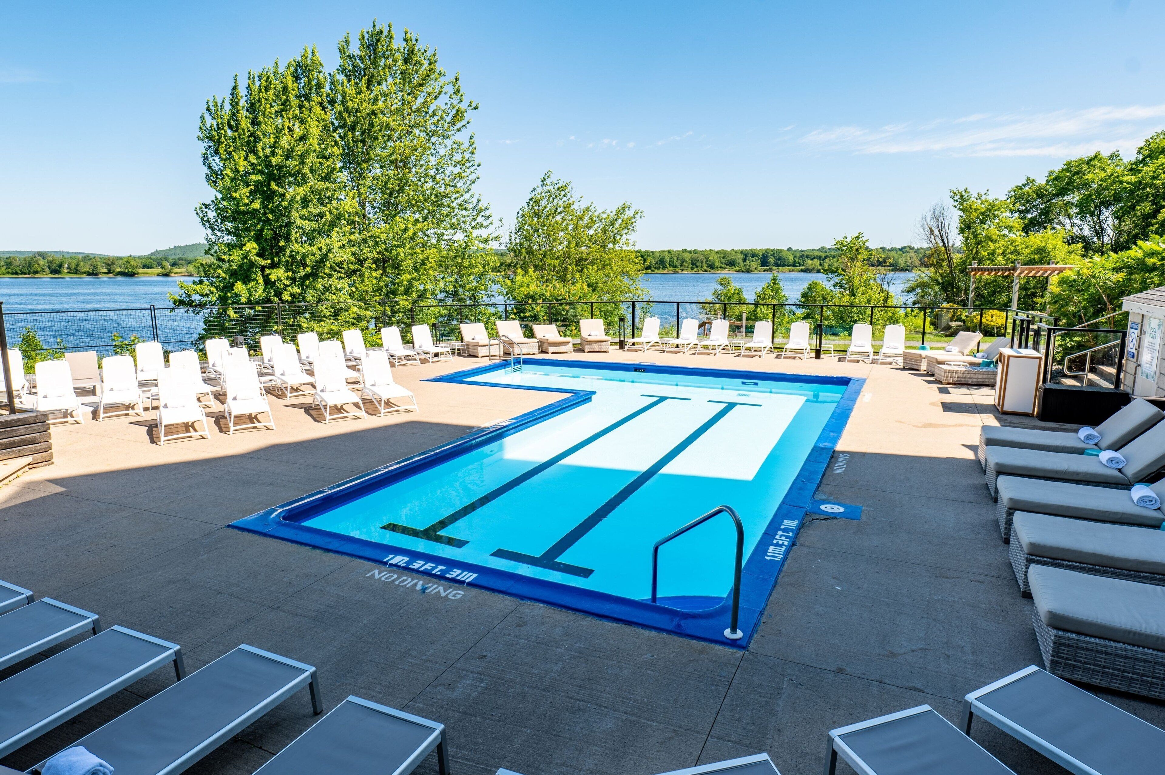 A swimming pool with lounge chairs and a view of a lake.