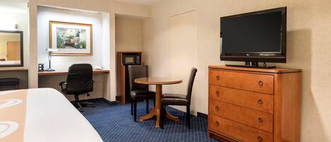 A hotel room with a bed, a desk, a chair, a television, and a dresser.