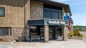 Exterior del Kodiak Inn, con fachada de piedra, ventanas amplias y un llamativo letrero de Best Western.