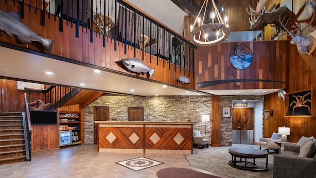 Un vestíbulo amplio con mostrador de recepción de madera, una escalera y un candelabro.