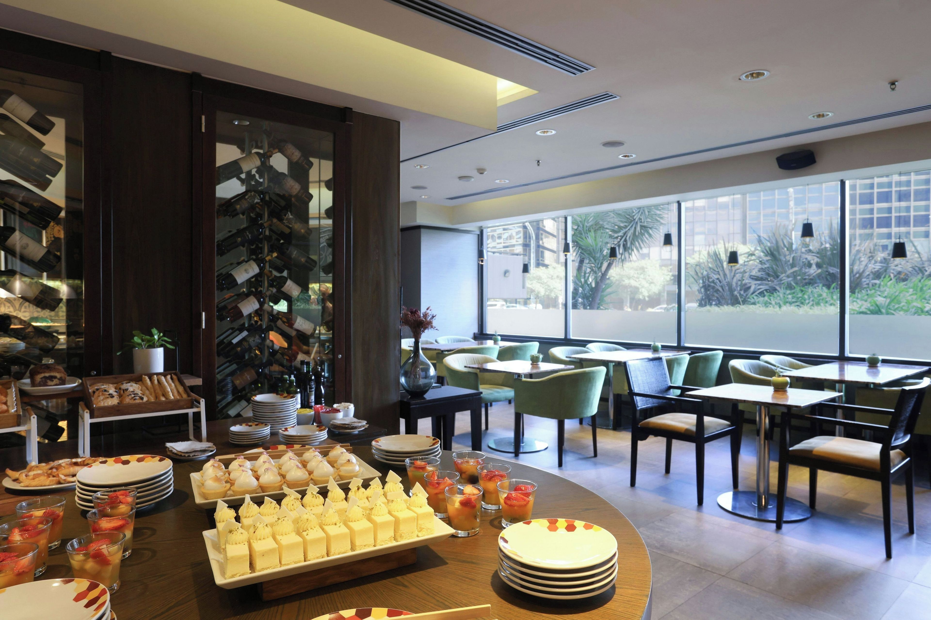 Un comedor con mesa de buffet, disposición de asientos y ventanas amplias.