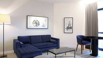 A modern living room with a blue sofa, a round table, and two framed pictures on the wall.