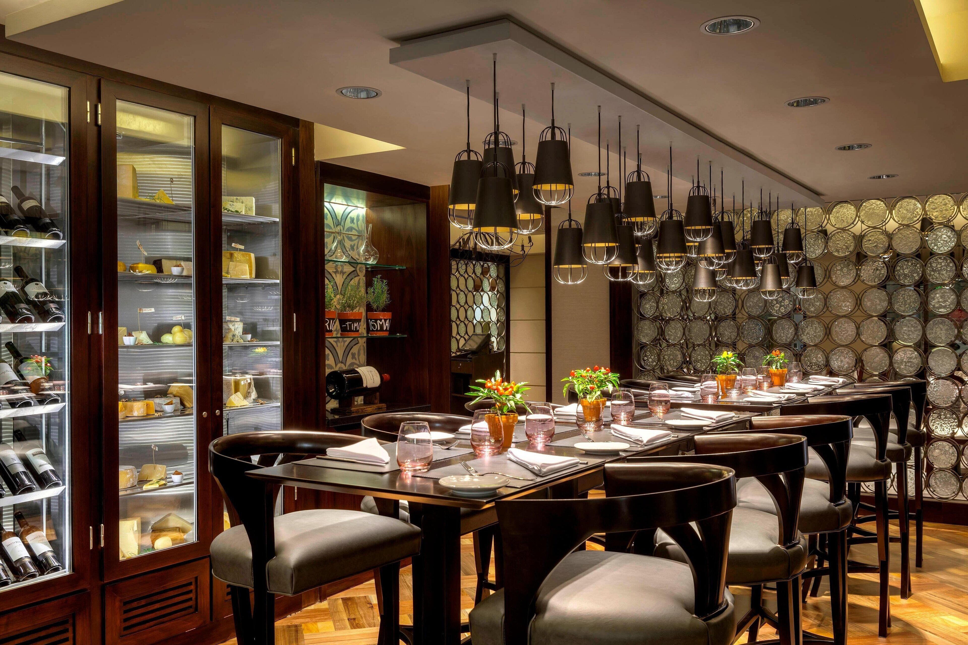 Un restaurante con una larga mesa de comedor, varias sillas y lámparas colgantes.