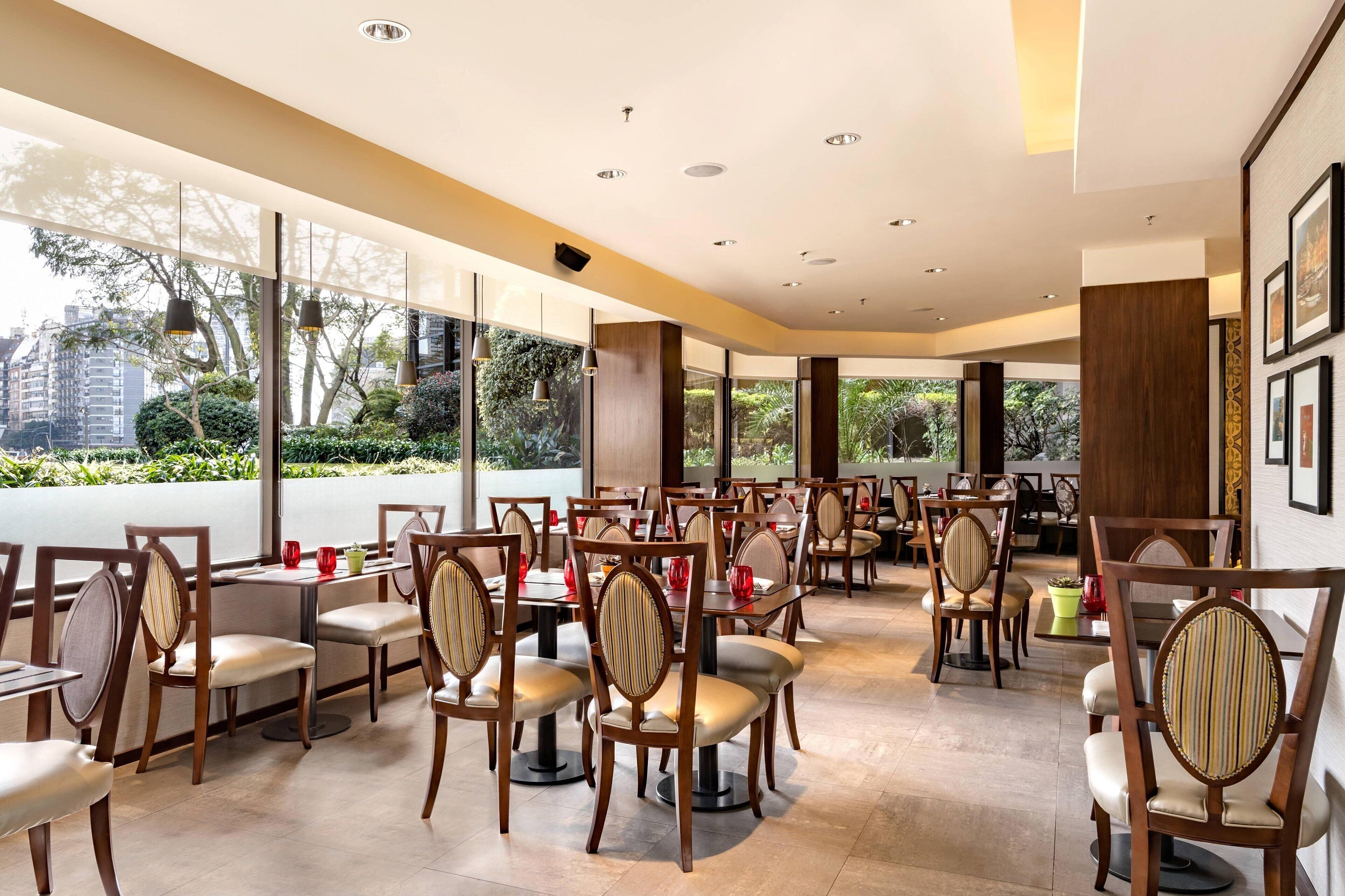 Un restaurant spacieux avec de hauts plafonds, de grandes fenêtres et une vue sur la verdure environnante.