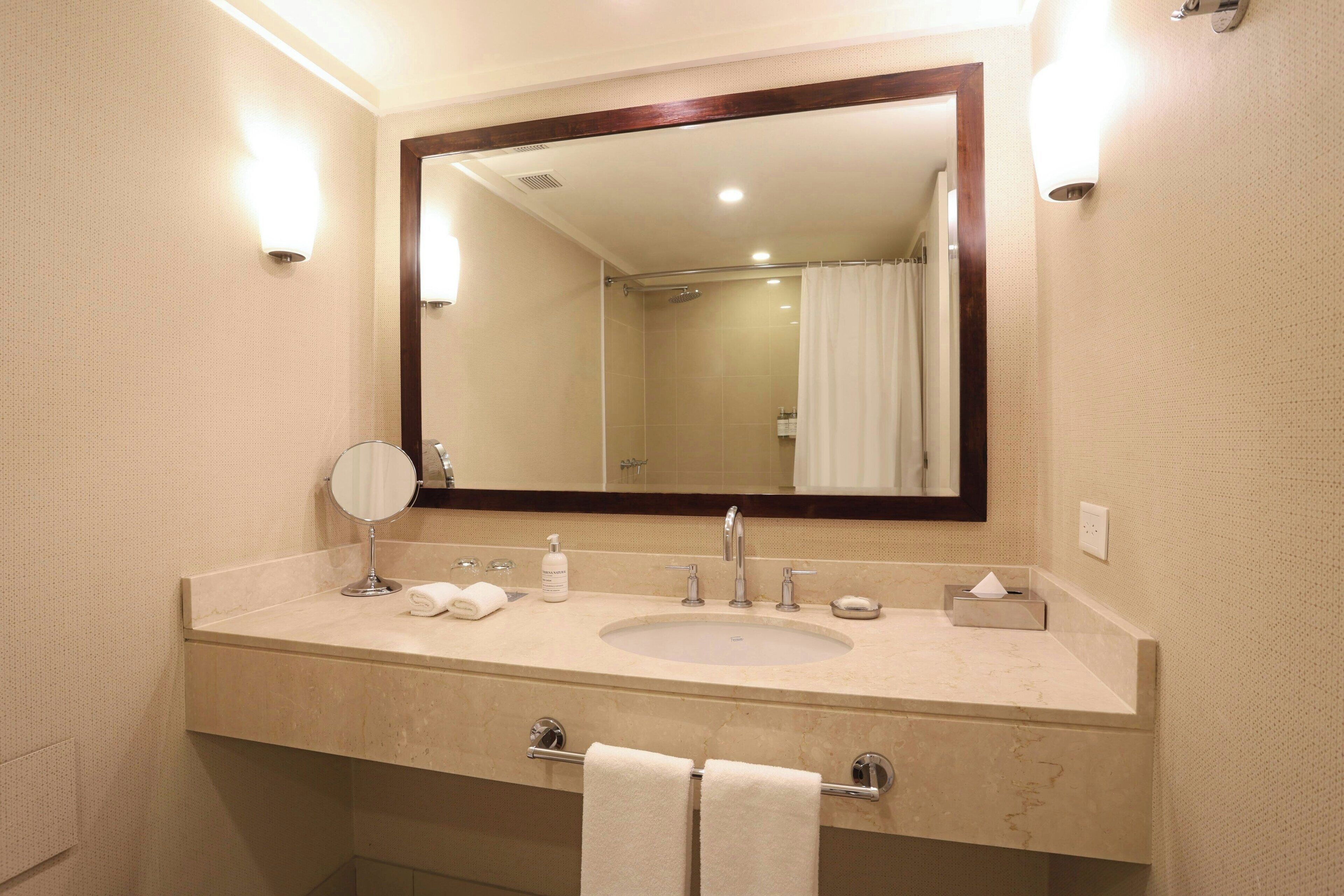 Une salle de bain avec un grand miroir, un lavabo, un porte-serviettes et un espace douche.