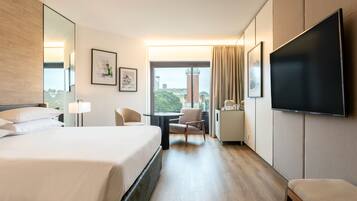 Una habitación de hotel con una cama grande, un escritorio, una silla, un televisor y una ventana con cortinas.