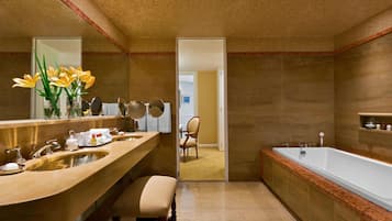 A bathroom with a double sink vanity, a large mirror, a bathtub, and a chair.