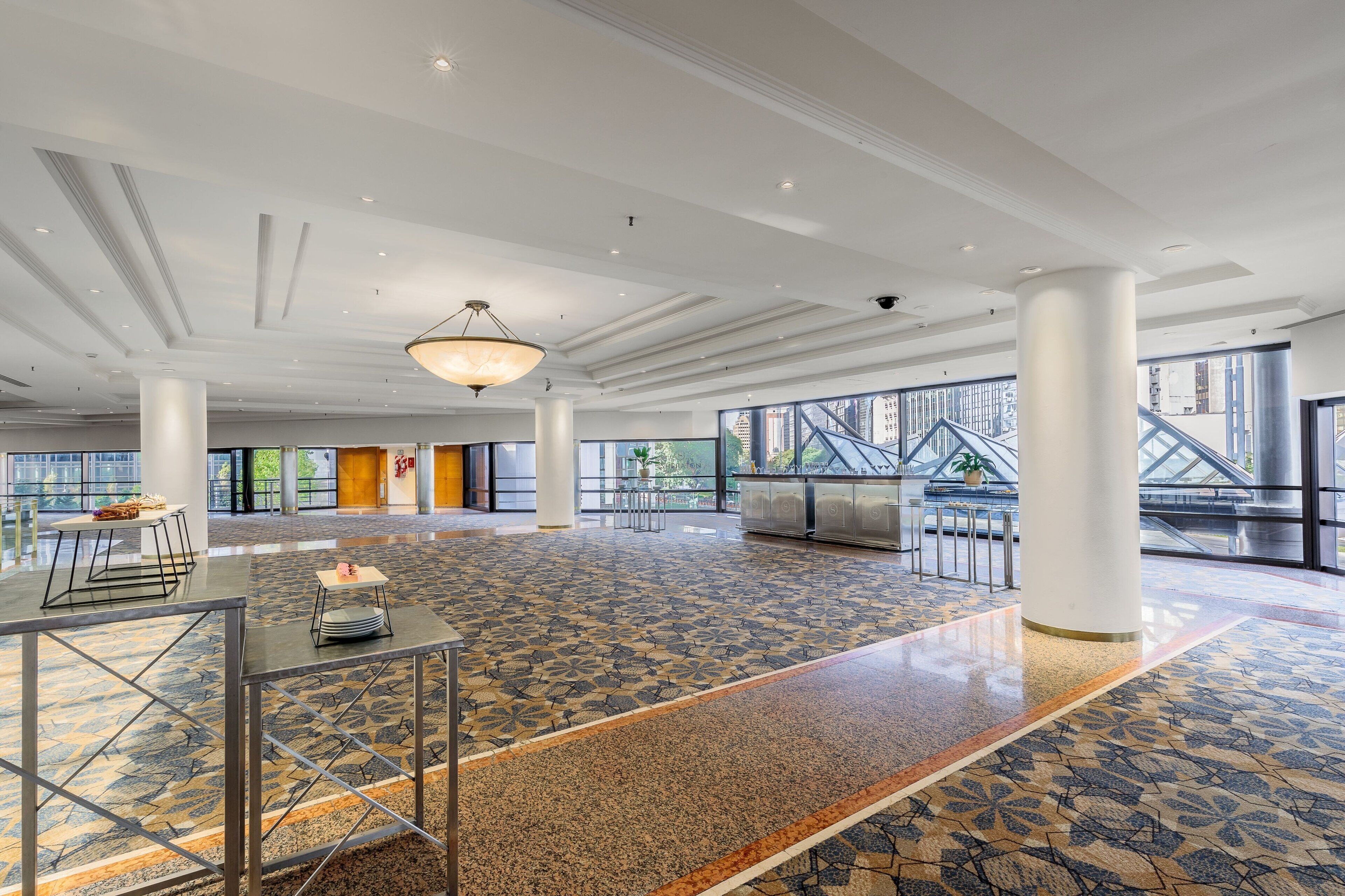 A spacious lobby with a patterned floor, large windows, and a modern chandelier.