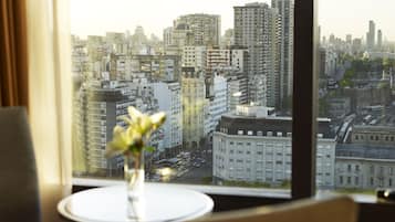 A cityscape through a window with a vase of flowers on a table.