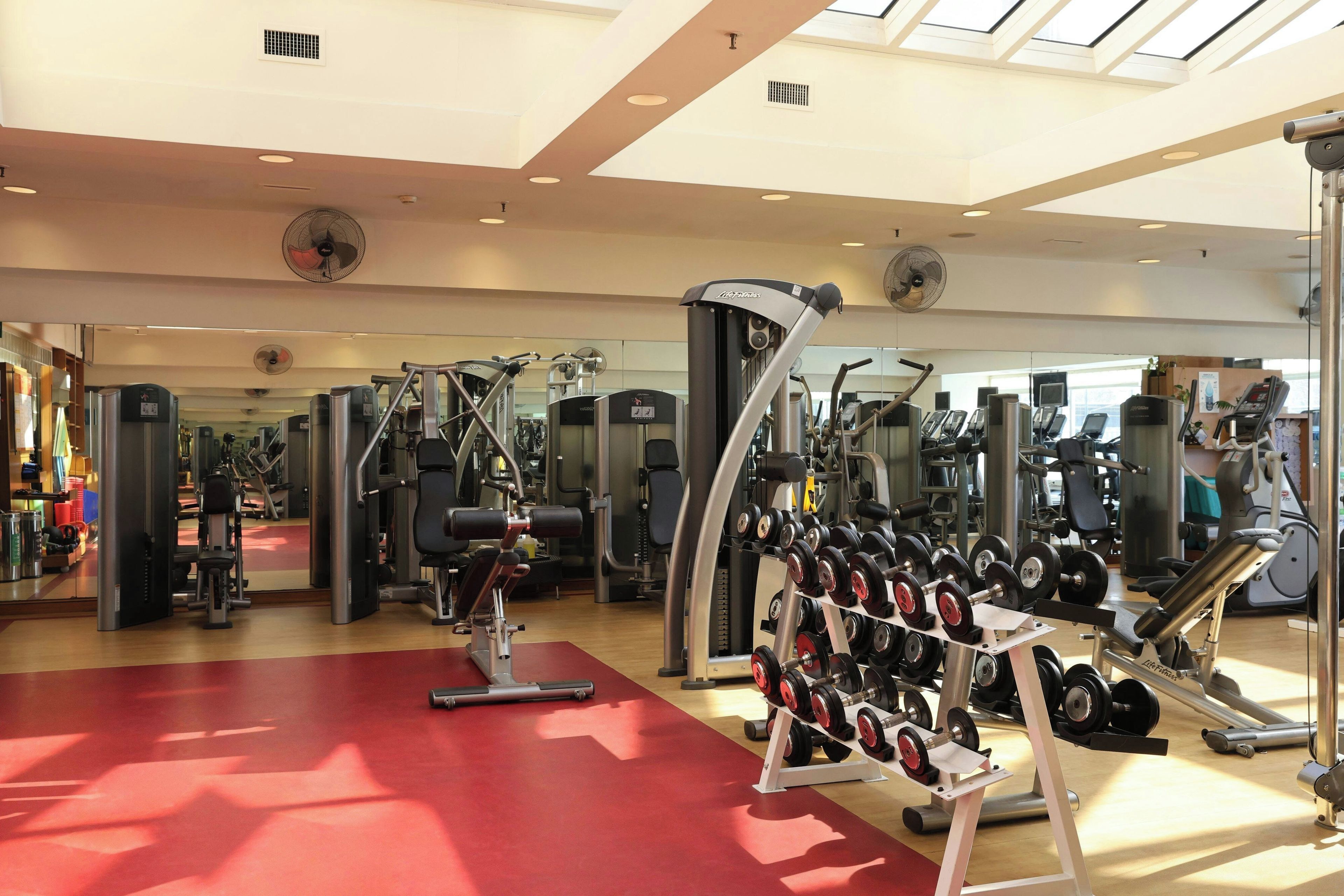 Une salle de sport équipée de divers appareils d’exercice, notamment des machines de musculation et des haltères.