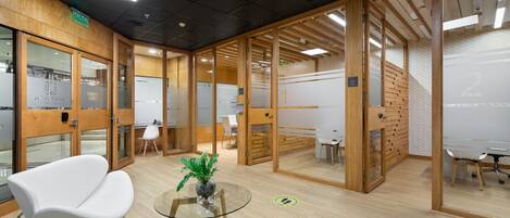 An office space with glass partitions, wooden walls, and a modern white chair.