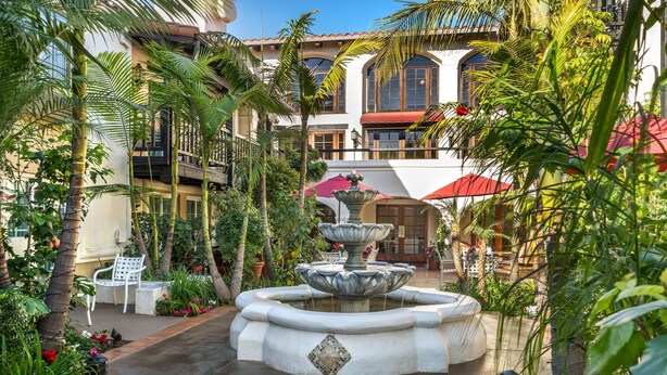 Un patio con una fuente, palmeras y un edificio con balcones.
