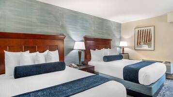 A hotel room with two beds, a large wall painting, a nightstand with a lamp, and a telephone.