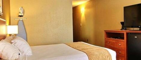 A hotel room with a bed, a television, a dresser, and a wall-mounted light.