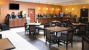 A restaurant with multiple tables and chairs, a counter with a cash register, and hanging pendant lights. - Quality Inn Thief River Falls (Thief River Falls)