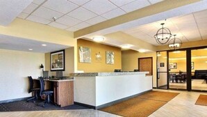 A reception area with a reception desk, chairs, a computer, and a wall-mounted clock. - Quality Inn Thief River Falls (Thief River Falls)