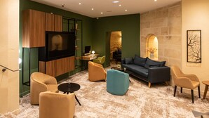 A modern living room with a flat-screen TV, comfortable seating, a stone wall, and a fireplace.