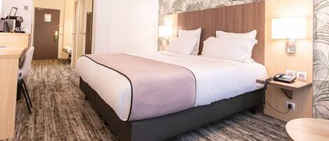 Una habitación de hotel con cama, lámparas de noche, escritorio y una silla.