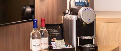 A hotel reception desk with a Nespresso machine, a bottle of Abatilles, a bottle of water, and a room service card holder.