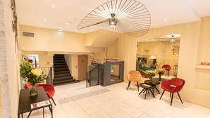 A hotel lobby with a staircase, seating area, and a modern ceiling light fixture.