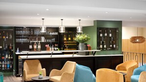 A bar area with seating, a counter with bottles, and a green wall.